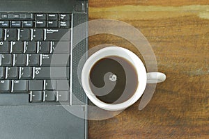 Computer notebook and black coffee cup on table