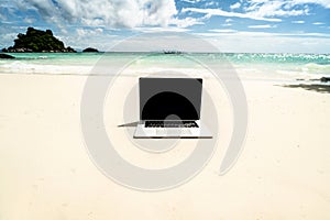 Computer notebook with empty black screen on the sandy tropical beach - digital nomad concept