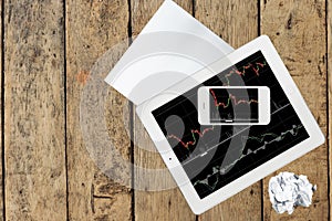 Computer, paper, smartphone and tablet with graph on wood table