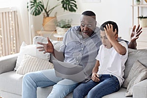Computer Problem. Shocked Black Boy And His Grandfather Looking At Laptop Screen