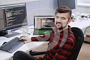 Computer programmer developer working in IT office, sitting at desk and coding, working on a project in software