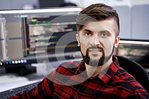 Computer programmer developer working in IT office, sitting at desk and coding, working on a project in software