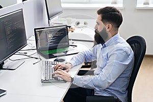 Computer programmer developer working in IT office, sitting at desk and coding, working on a project in software