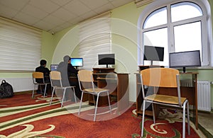 Computer room. Two boys sitting at desks in front of monitors of computers