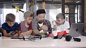 Computer science research class with Asian specialist and three pupils at primary school