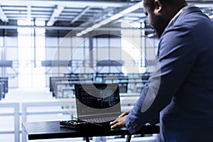 Computer scientist in data center using laptop to visualize AI tech