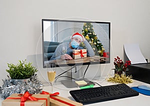 Computer screen with Sad man with face mask home alone on video call missing family at christmas