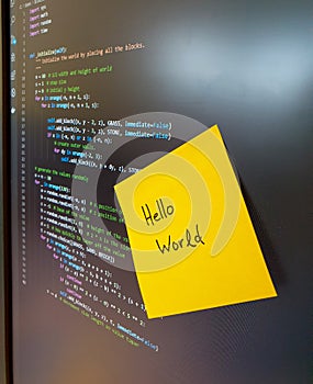 Computer screen showing python code with yellow sticker saying hello world