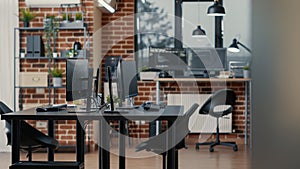 Computer screens on desk in empty data room and computers in background running programming code