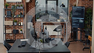 Computer screens on desk in empty software it agency office and computers in background