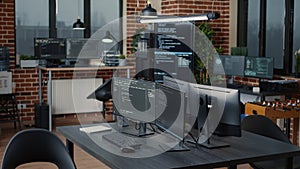 Computer screens running programming code in empty software it agency office and computers parsing data