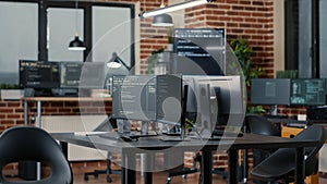 Computer screens running programming code in empty software developing agency office
