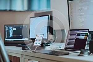 Computer screens running programming code in empty software developing agency office and computers parsing data