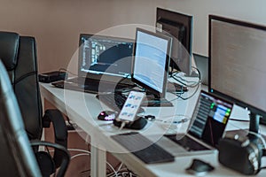 Computer screens running programming code in empty software developing agency office and computers parsing data