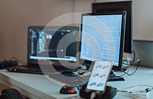 Computer screens running programming code in empty software developing agency office and computers parsing data