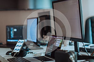 Computer screens running programming code in empty software developing agency office and computers parsing data
