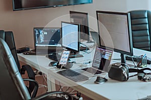 Computer screens running programming code in empty software developing agency office and computers parsing data