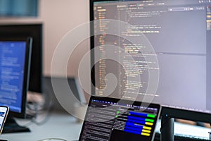 Computer screens running programming code in empty software developing agency office and computers parsing data