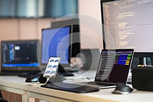 Computer screens running programming code in empty software developing agency office and computers parsing data