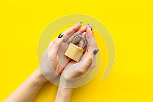 Computer system protection from hacker with locker in hands on yellow background top view space for text