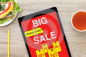 Computer tablet with big sale screen on wooden table cafe