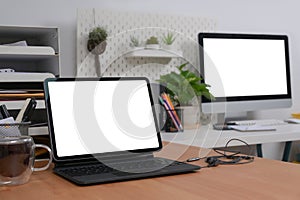 Computer tablet with blank screen on wooden table in home office.