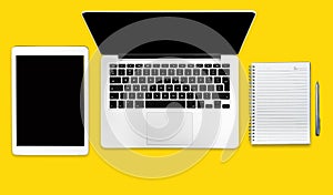 Computer tablet and notebook on a solid yellow background. Minimalistic flat lay composition