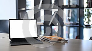 Computer tablet and notebooks on wooden table in modern office.