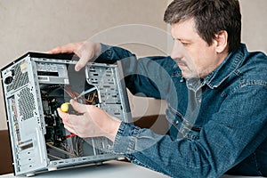 Computer technician engineer with screwdriver in his hand is repairing the personal computer.