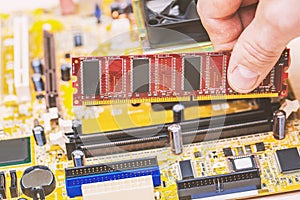 Computer technician installing computer memory RAM in the slot of the motherboard