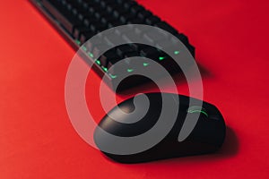 Computer wireless gaming mouse and keyboard with green backlight against red background