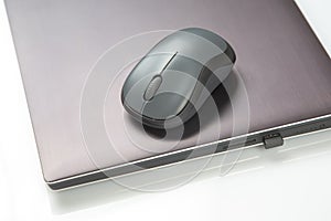 Computer wireless mouse next to a laptop on a white table close-up. electronic personal industry