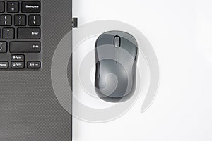 Computer wireless mouse next to a laptop on a white table close-up. electronic personal industry