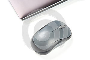 Computer wireless mouse next to a laptop on a white table close-up. electronic personal industry