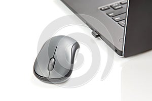 Computer wireless mouse next to a laptop on a white table close-up. electronic personal industry