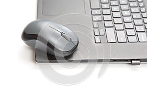 Computer wireless mouse next to a laptop on a white table close-up. electronic personal industry