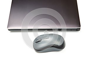 Computer wireless mouse next to a laptop on a white table close-up. electronic personal industry