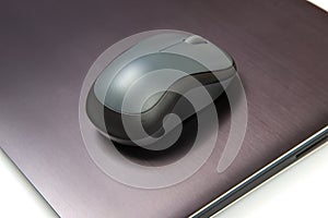 Computer wireless mouse next to a laptop on a white table close-up. electronic personal industry