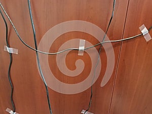 computer wires taped to a brown wood desk