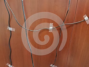 computer wires taped to a brown wood desk