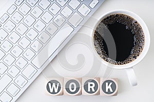 Computer work space with coffee and cubes with the word `work`