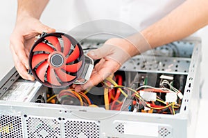 computer workshop. hand of repairman installs a cooler in in a computer