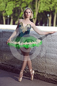 Concentrated Abashed Winsome Artistic Professional Caucasian Ballet Dancer in Green Tutu Dress Posing Near River in Summer Park