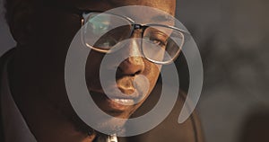 Concentrated African American businessman in eyeglasses in front of laptop with reflection of display in eyeglasses