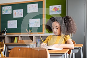 Concentrated African American girl doing exam at classroom