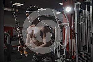 Concentrated african american sportsman training muscles in gym. Motivated bodybuilder on workout