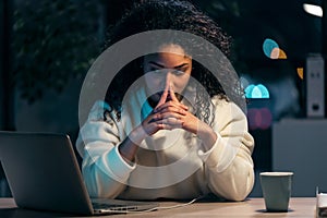 Concentrated african business woman thinking while working with laptop in the office at home