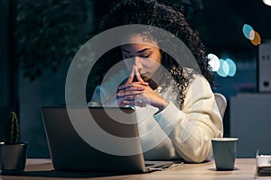 Concentrated african business woman thinking while working with laptop in the office at home