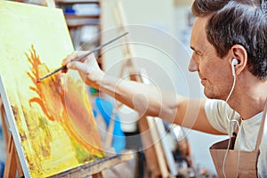 Concentrated artist painting a picture in cozy studio