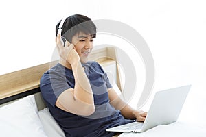 Concentrated asian man wearing earphones, listening to favorite music